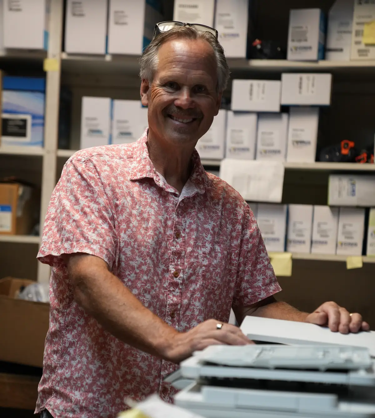 George Simmons with his hands on an office multifunction copier in the shop