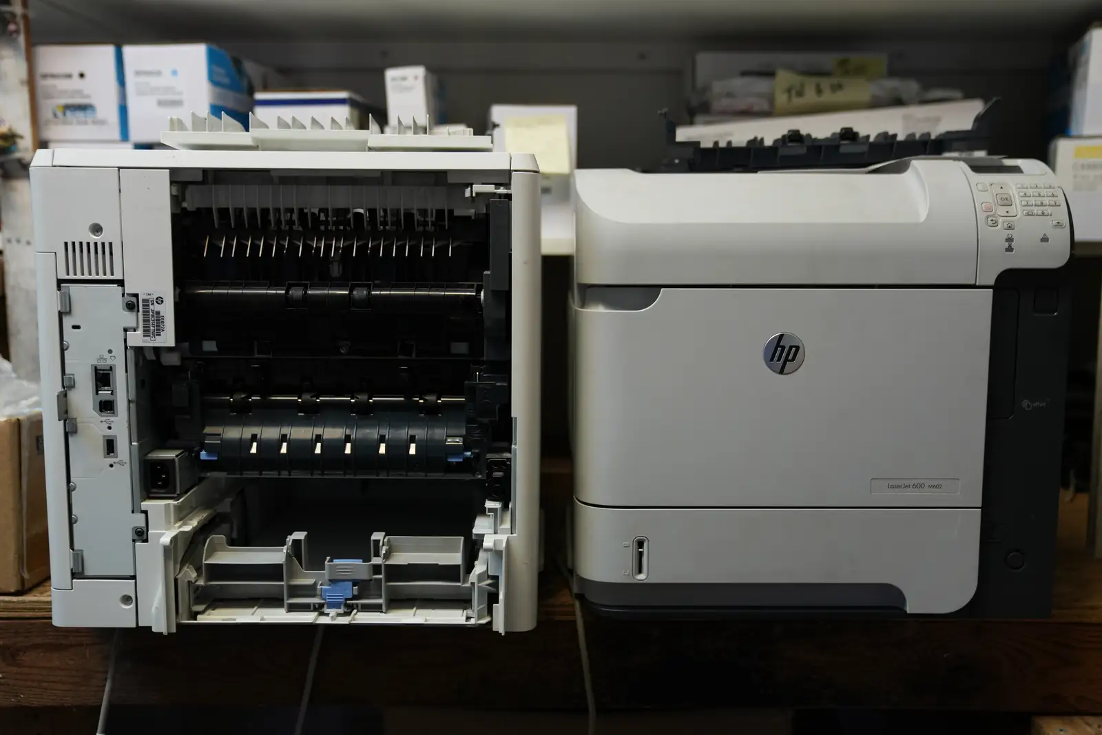 Two HP LaserJet printers on the bench, one opened up for repair
